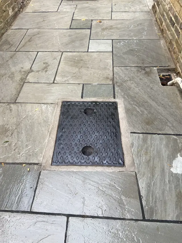 Recessed manhole cover set into stone paving