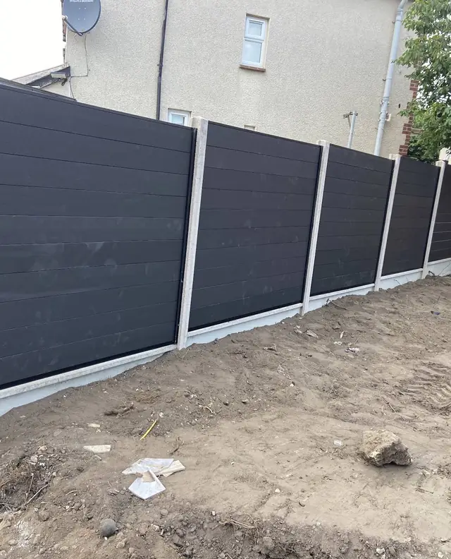 Charcoal composite fence panels set between concrete posts and gravel boards