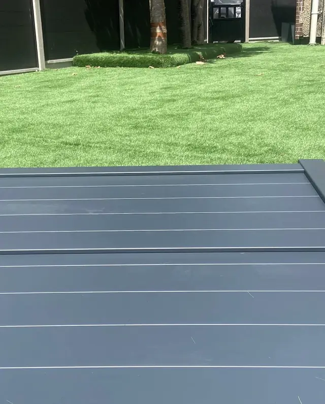 Grey composite decking edge looking out over a new artificial lawn