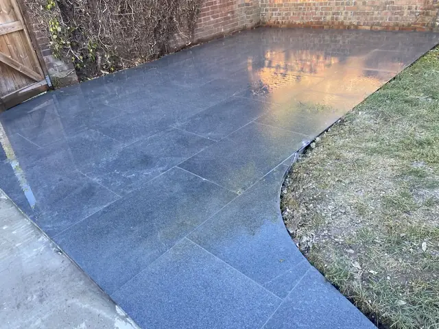 Newly laid dark slate patio with a curved edge beside a lawn